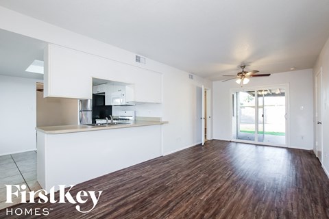 A spacious room with wooden flooring and a ceiling fan.