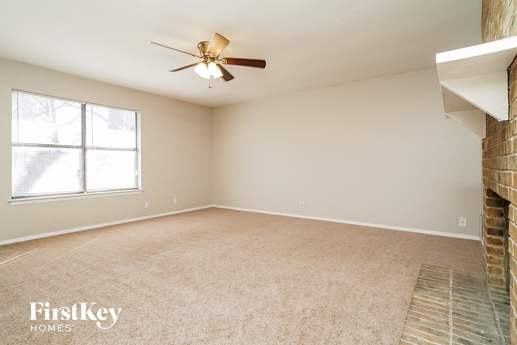 an empty living room with a ceiling fan and a window