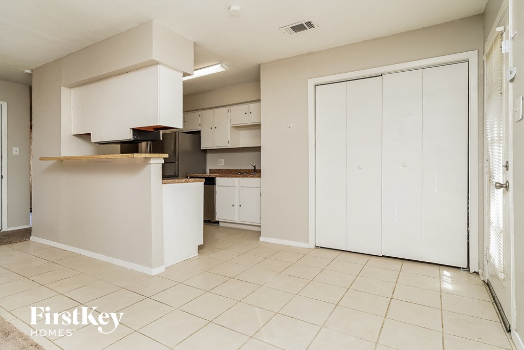 an empty kitchen with white cabinets and a white door