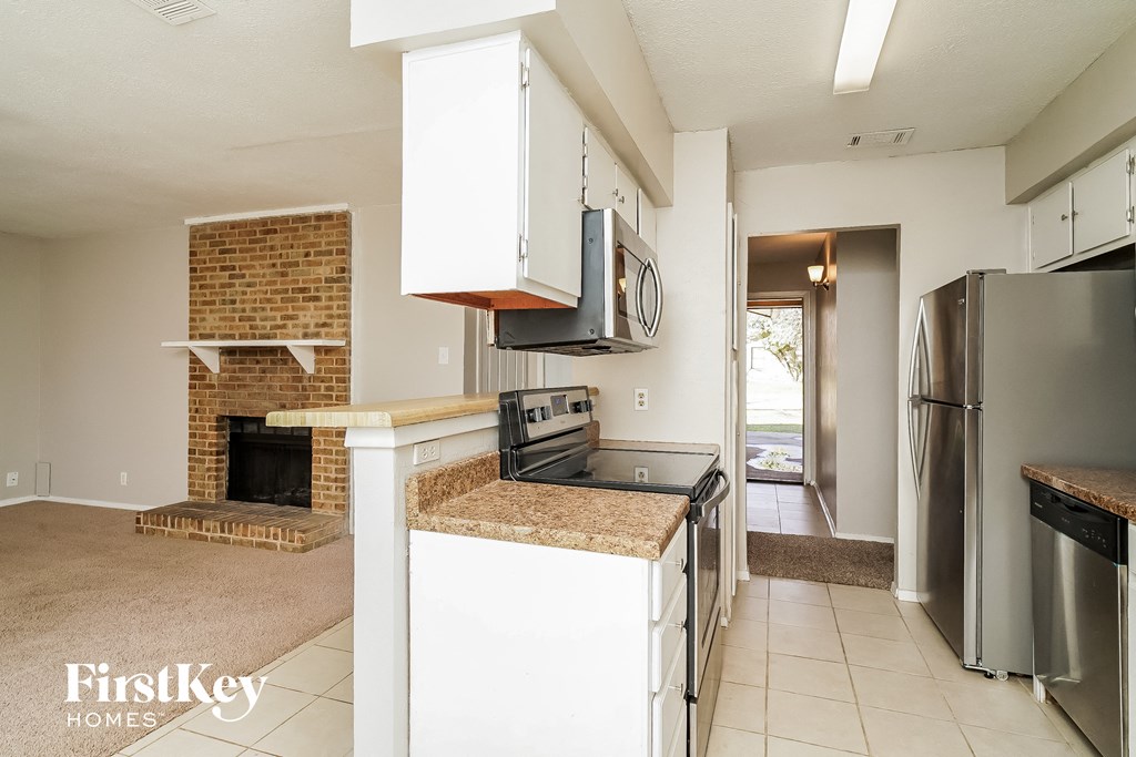 a kitchen with white cabinets and a stove and a fireplace