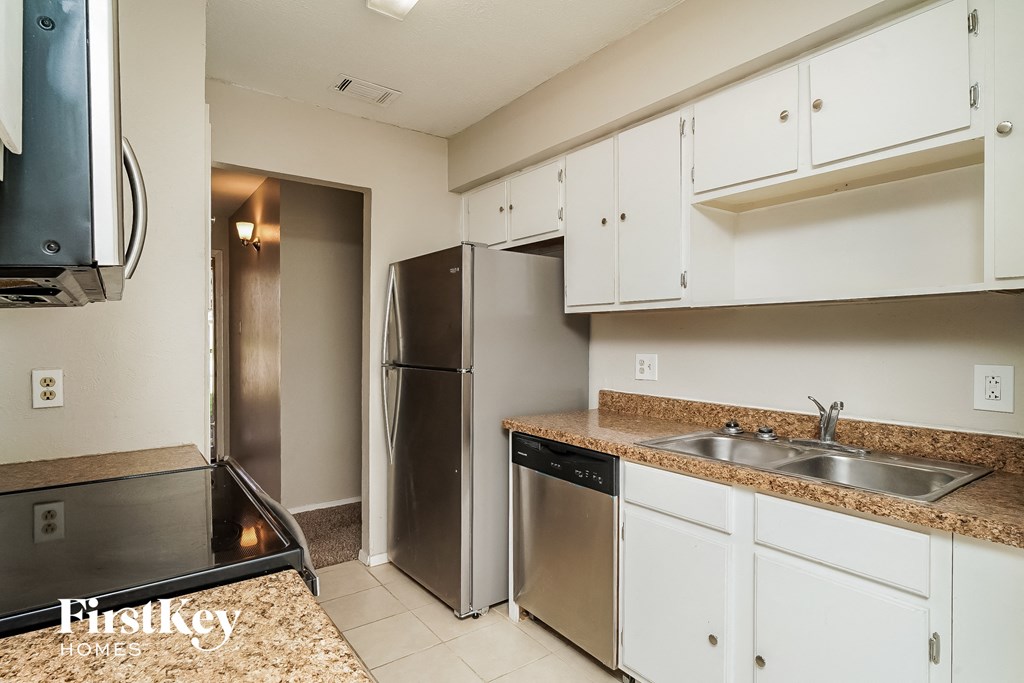 a kitchen with white cabinets and a stainless steel refrigerator