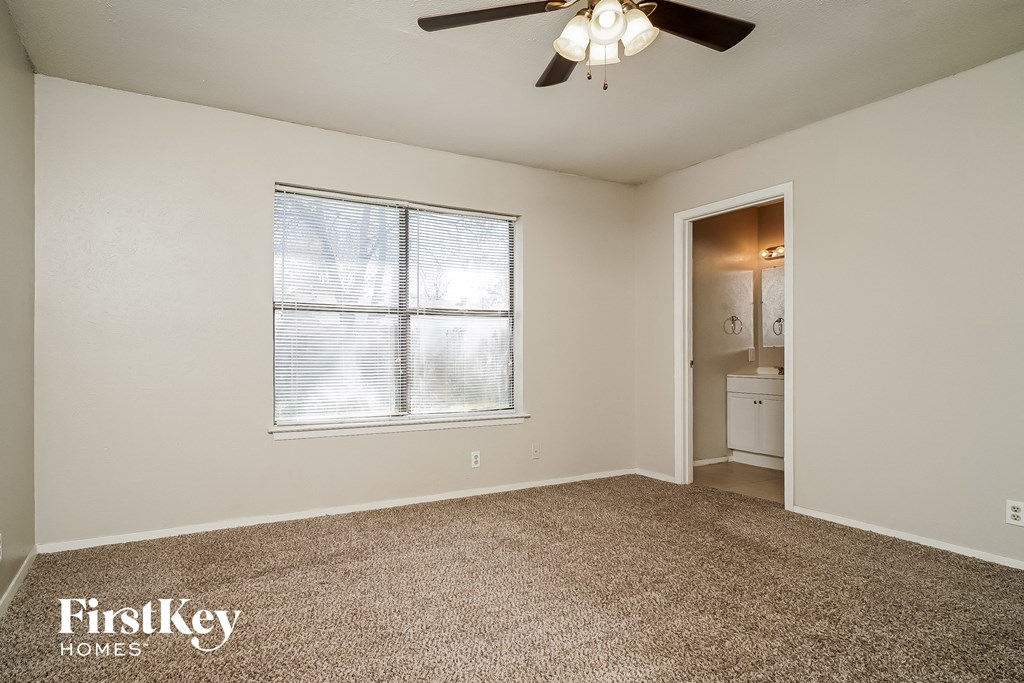 the living room of an empty house with a window and a ceiling fan