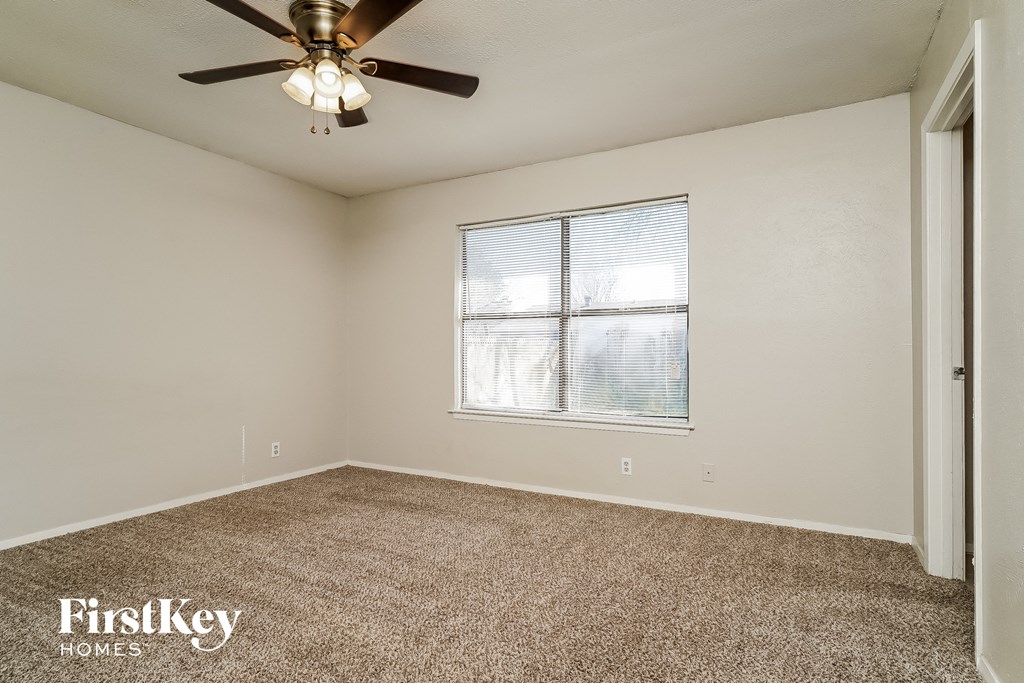 the living room of an empty house with a ceiling fan and a window