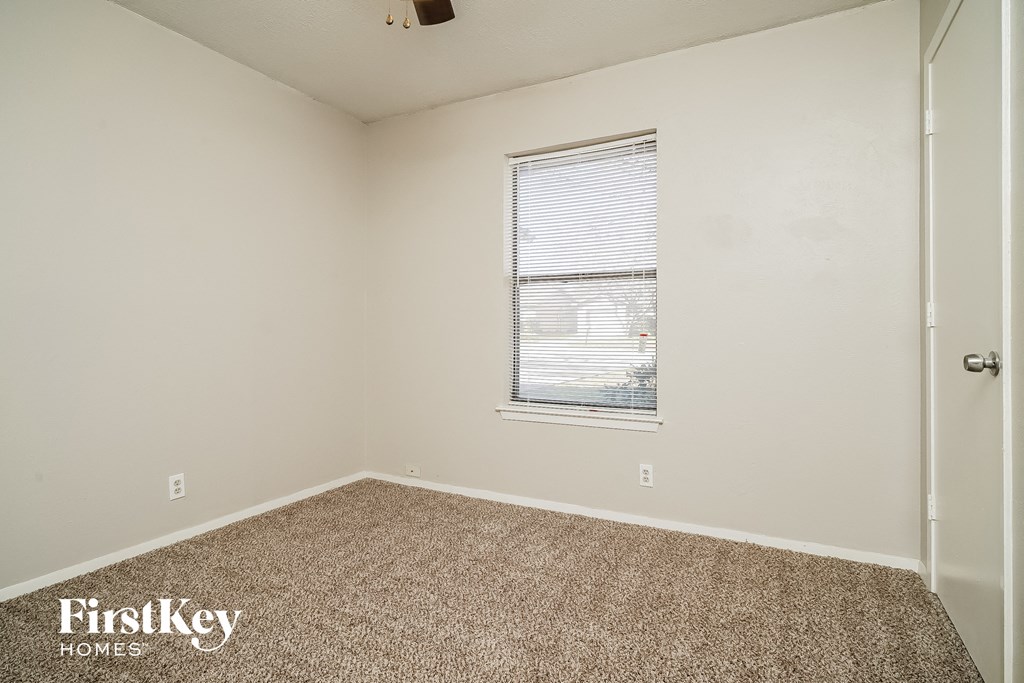 the bedroom of an apartment with carpet and a window