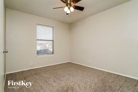 the spacious living room of an updated home with carpet and a ceiling fan