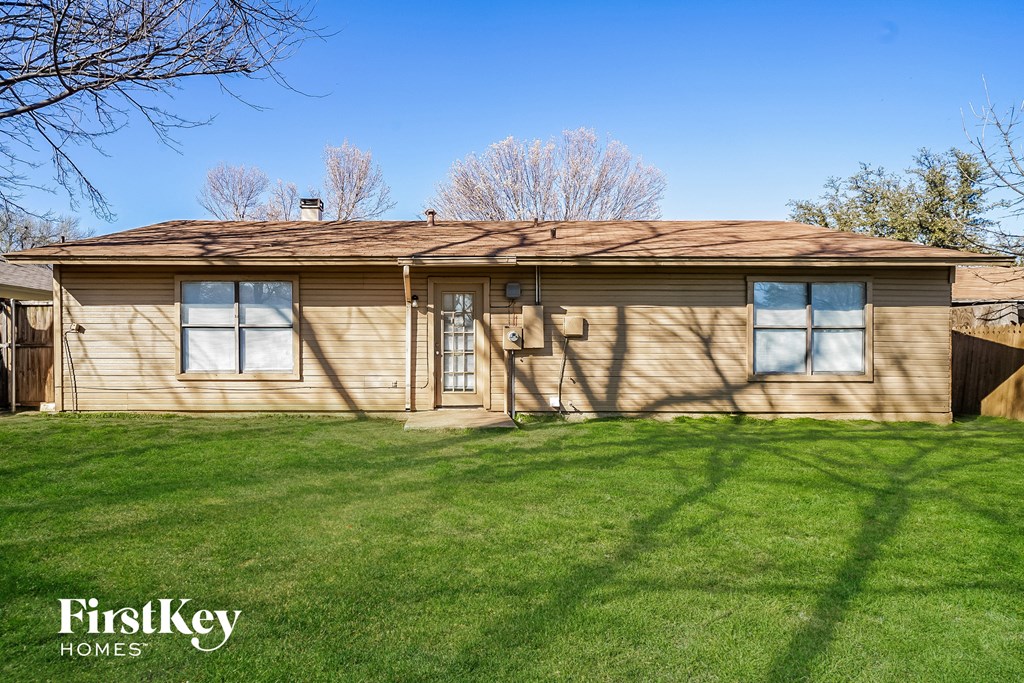 a tan house with a brown roof on a grass yard