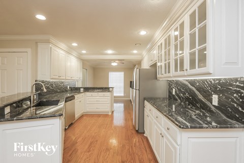 A kitchen with white cabinets and a marble countertop.
