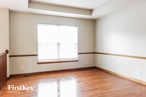 a bedroom with wood floors and white walls and a window