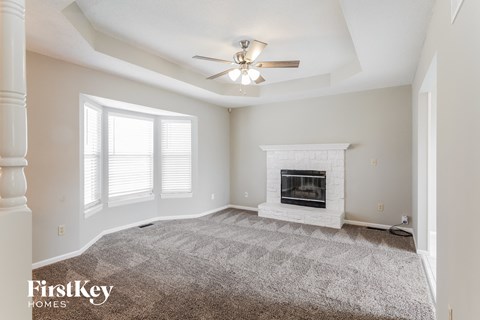 A spacious living room with a fireplace and a carpet on the floor.