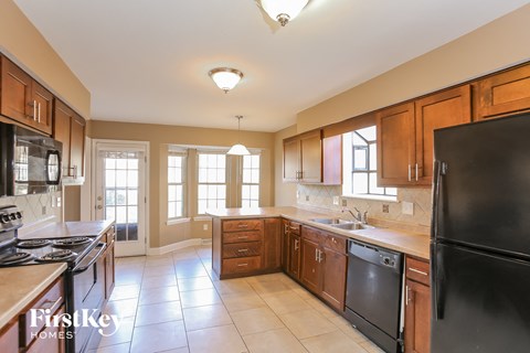 a kitchen with wood cabinets and black appliances and tiled floors
