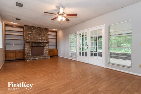 an empty living room with a fireplace and a ceiling fan