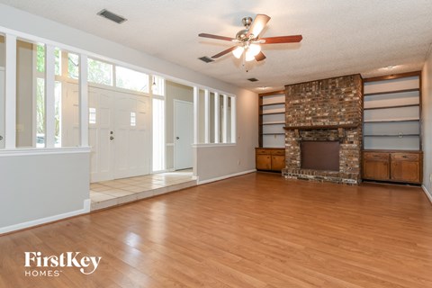 an empty living room with a fireplace and a ceiling fan