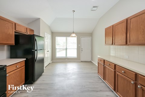 A kitchen with wooden cabinets and a black fridge.