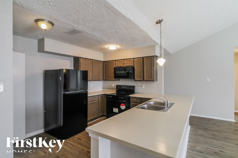 A kitchen with a black fridge and a white counter top.