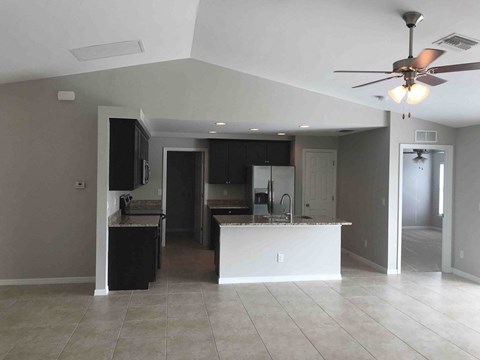 A kitchen with a white island and a ceiling fan.