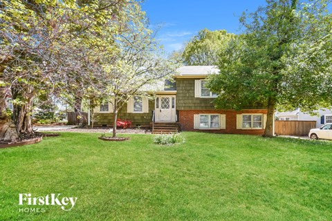 A house with a green lawn and trees in the front yard.