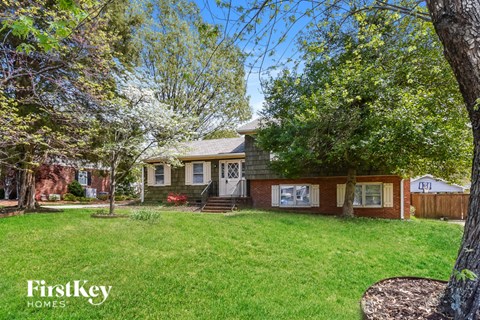 A house with a lawn and trees in front of it.