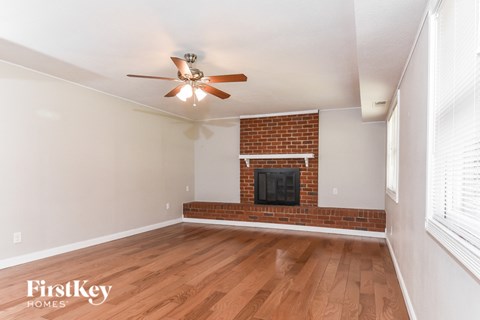 A room with a brick fireplace and a ceiling fan.
