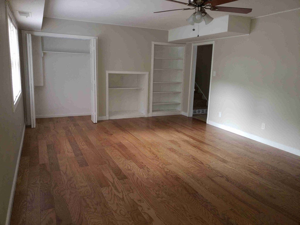 an empty living room with wooden floors and a closet