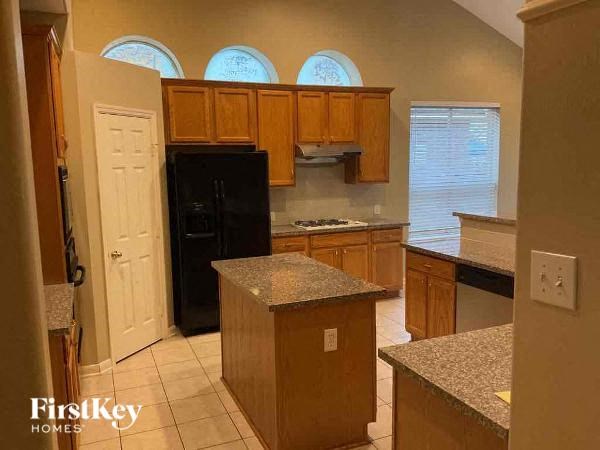 A kitchen with wooden cabinets and a black refrigerator.