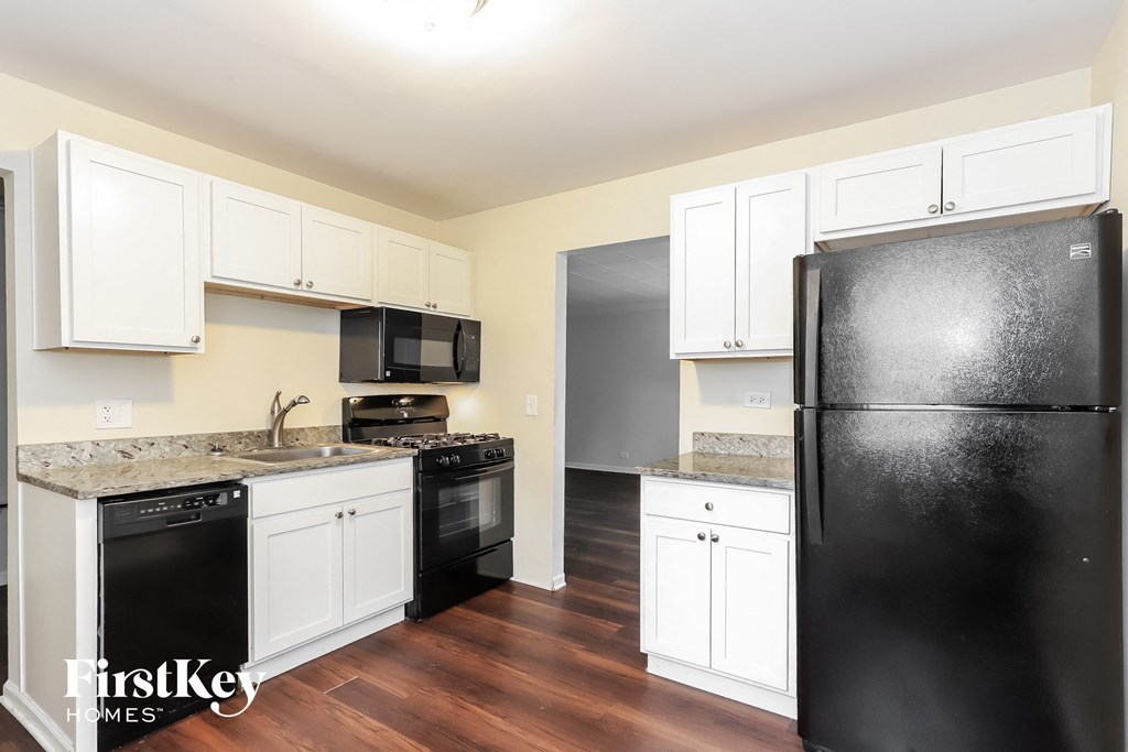 a kitchen with white cabinets and black appliances