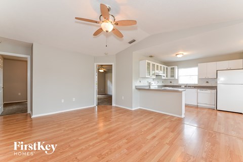 A spacious kitchen and living room with wooden floors and white walls.