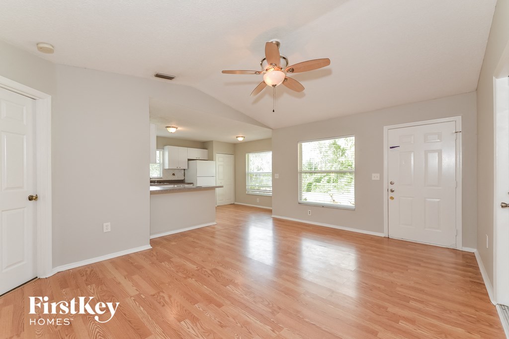 A spacious room with wooden flooring and a ceiling fan.