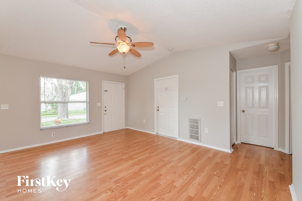 A room with a ceiling fan and wooden floors.