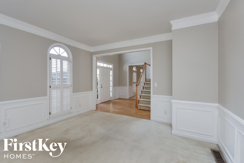 A spacious room with a staircase and a window with blinds.