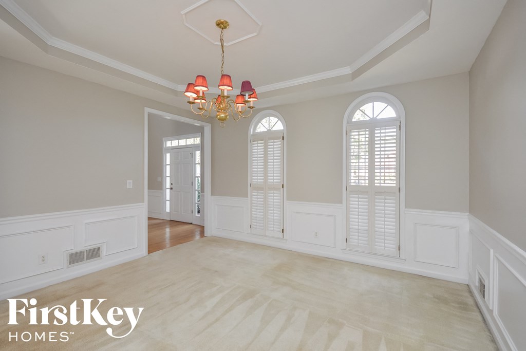 A room with a chandelier and a window with blinds.