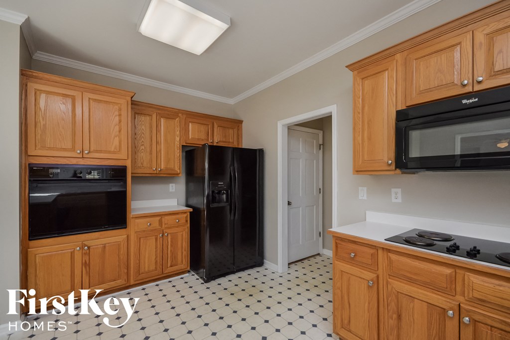 A kitchen with wooden cabinets and a black fridge.