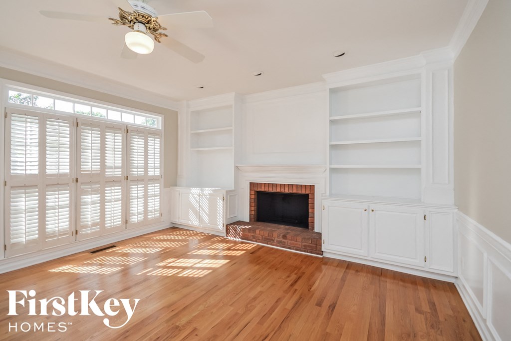 A spacious living room with a fireplace and wooden floors.