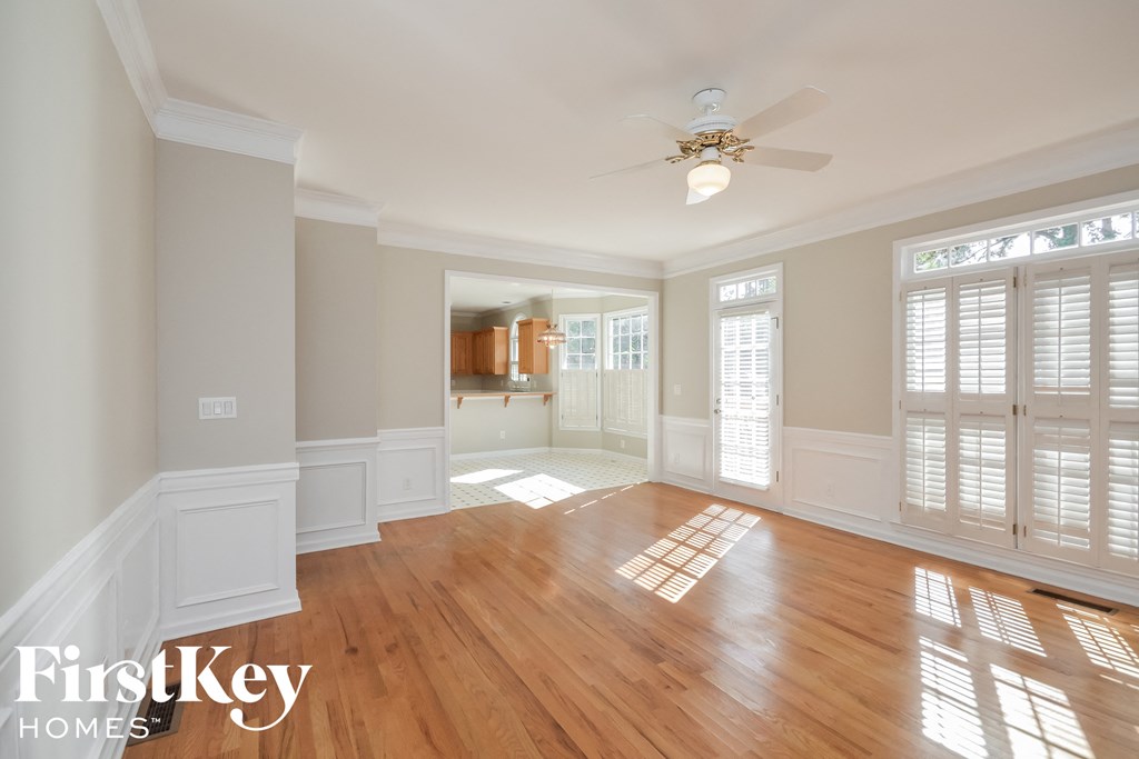 A spacious room with wooden floors and a ceiling fan.
