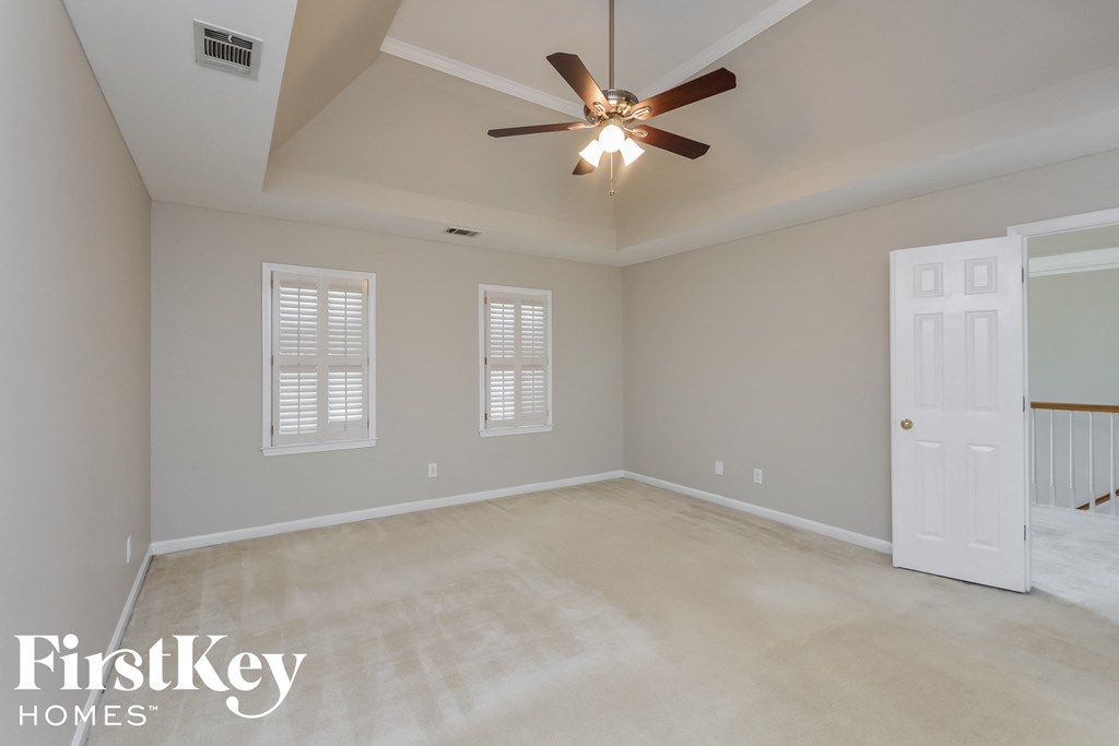 A room with a ceiling fan and a door leading to another room.
