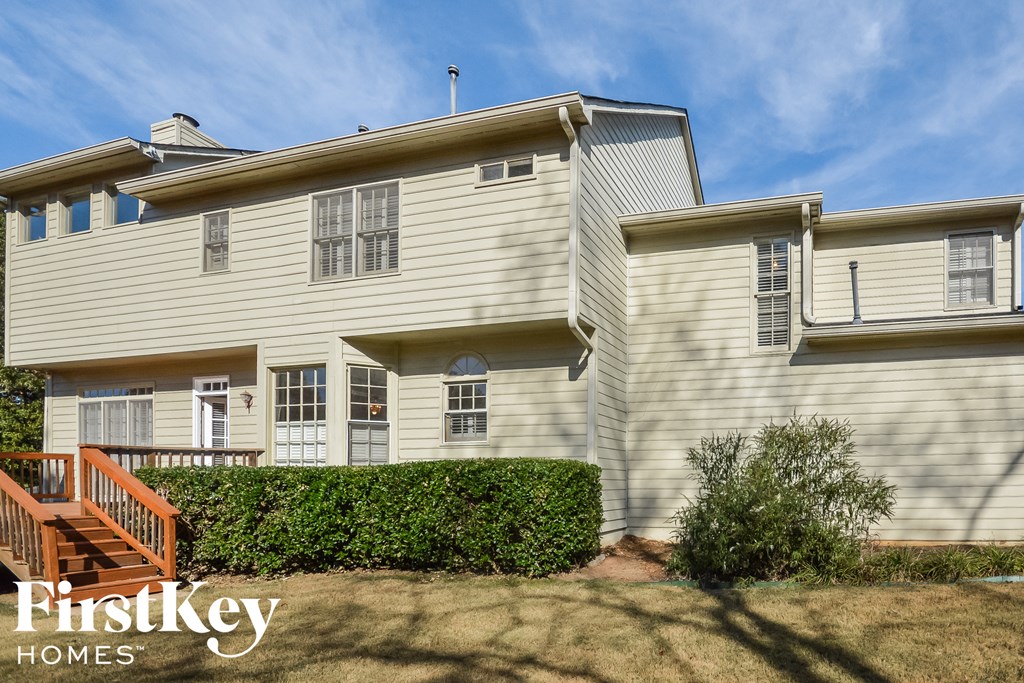 A two-story house with a white exterior and a brown staircase.