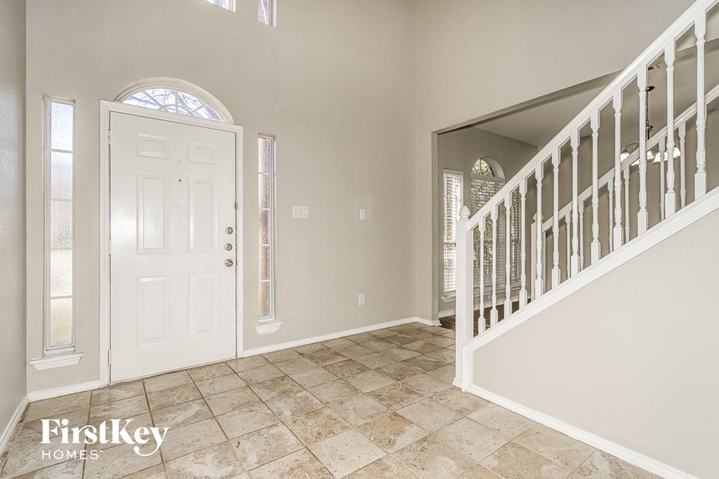 the entryway of a home with a white door and a staircase