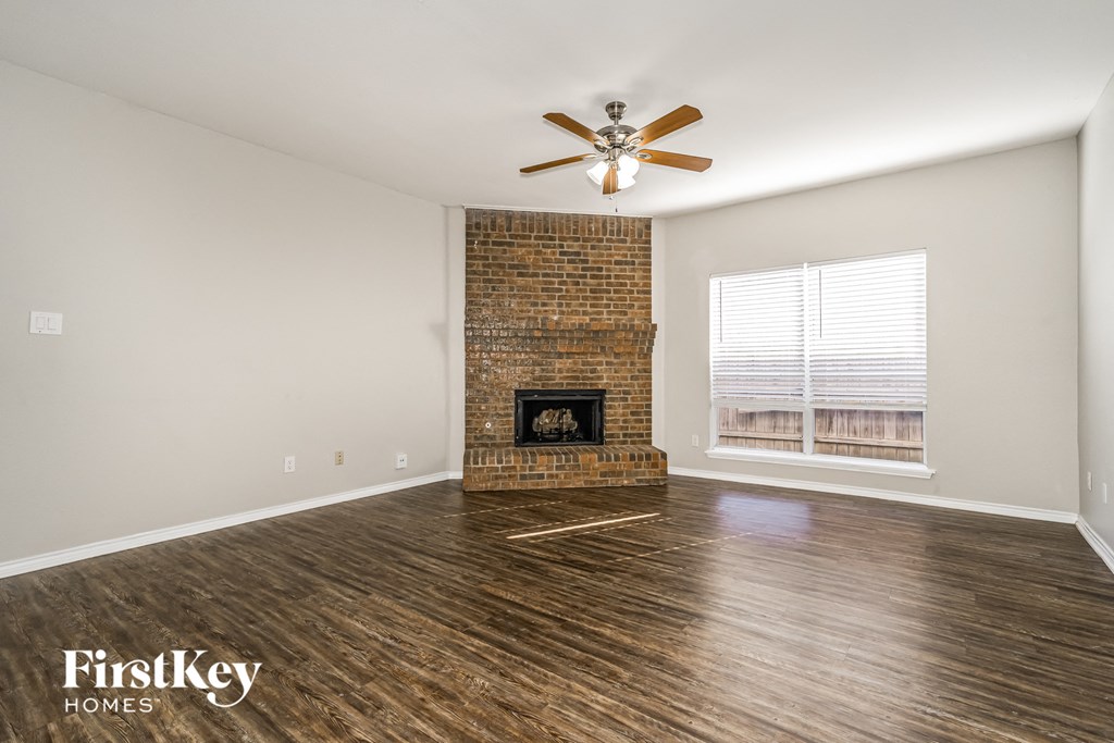 a living room with a brick fireplace and a ceiling fan