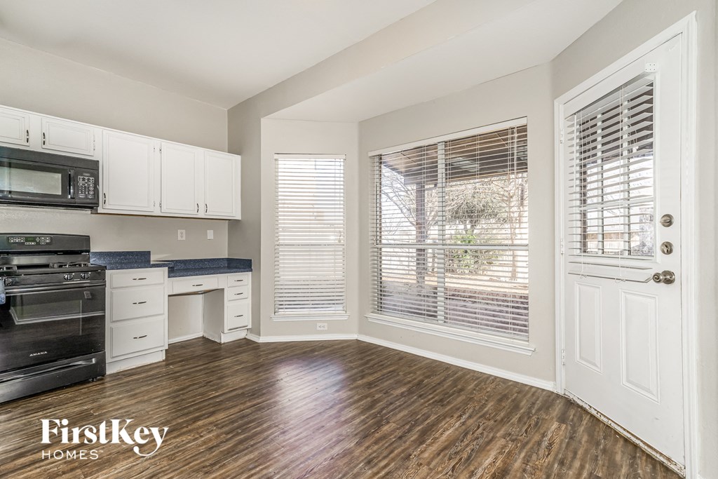 a kitchen with white cabinets and black appliances and a large window