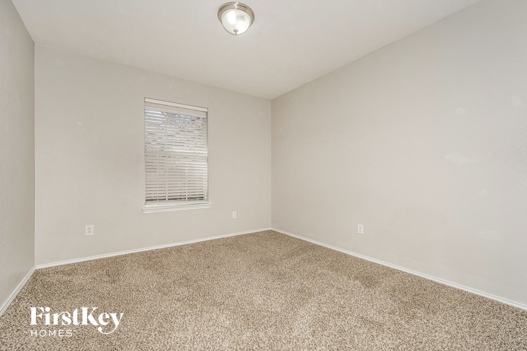 the living room of an empty house with carpet and a window