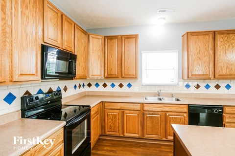 A kitchen with wooden cabinets and a black stove top oven.