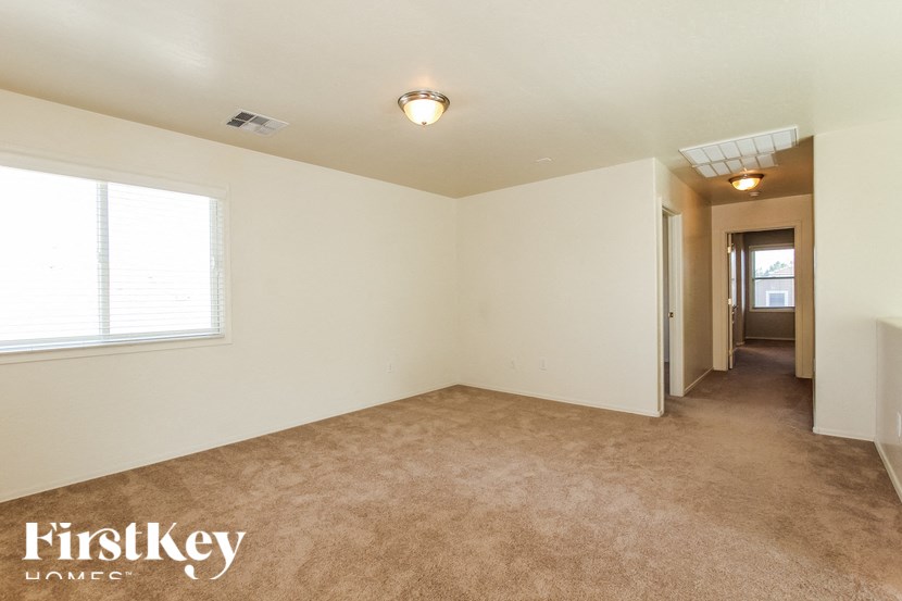 A spacious room with a carpeted floor and a window on the left side.