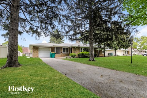A house with a driveway and trees in front of it.