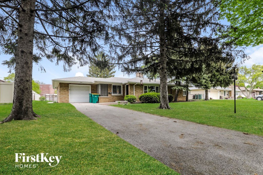 A house with a driveway and trees in front of it.