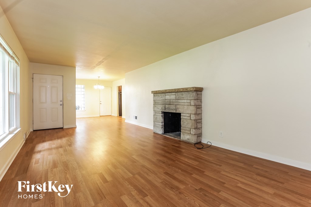 A room with a stone fireplace and wooden floors.