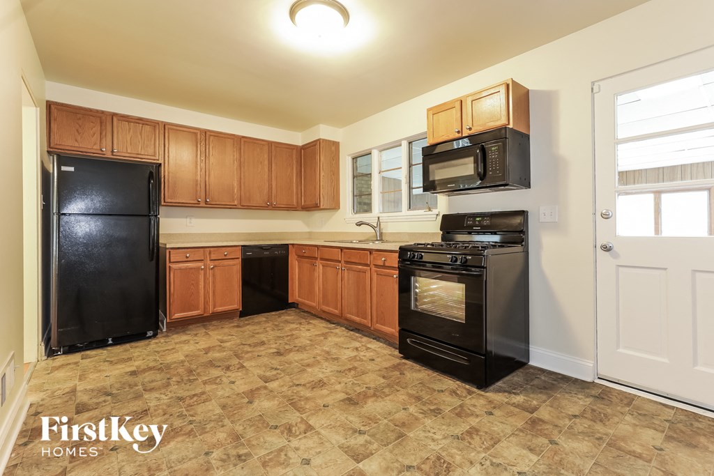A kitchen with black appliances and wooden cabinets.