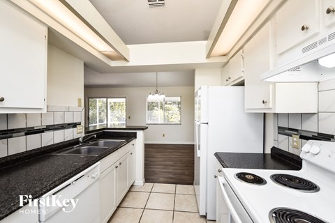 A kitchen with white cabinets and black countertops.