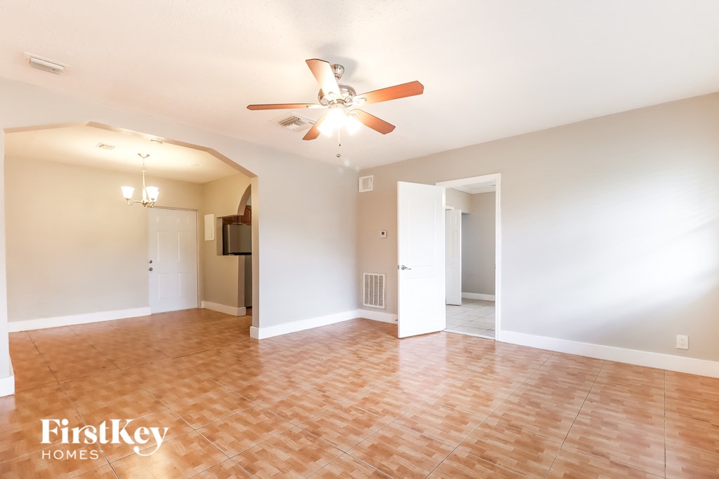 an empty living room with a ceiling fan and wood floors