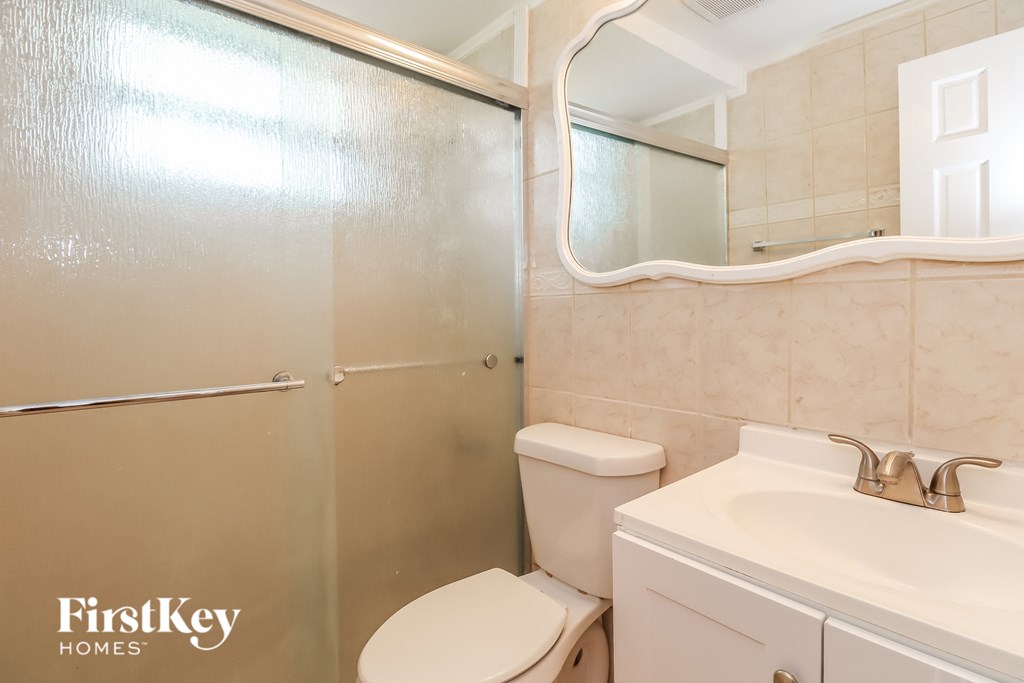 a white bathroom with a shower toilet and sink