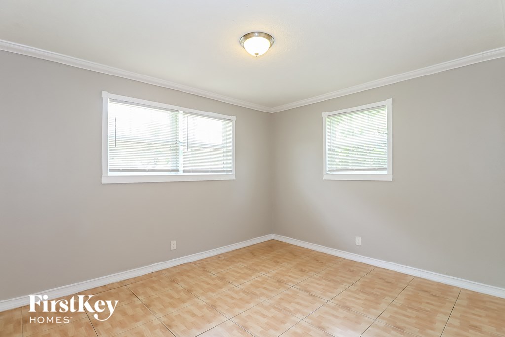 a empty room with two windows and a wooden floor