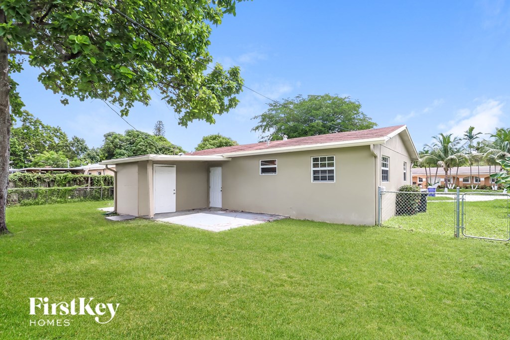 a small house with a yard and a chain link fence